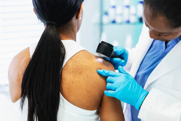 Female dermatologist screening patient for skin cancer.
